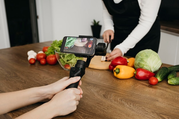 Blogger femenina grabando a sí misma mientras prepara la comida