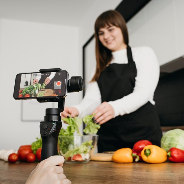 Blogger femenina grabando a sí misma mientras prepara la ensalada