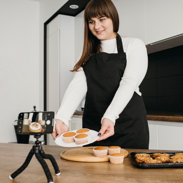 Blogger femenina grabando a sí misma mientras prepara muffins