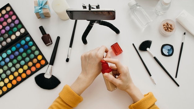 Blogger femenina que transmite base de maquillaje en línea con un teléfono inteligente