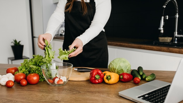 Blogger femenina streaming cocinar en casa con portátil