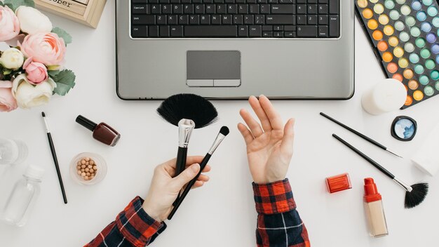 Blogger femenina streaming de productos de maquillaje online con portátil