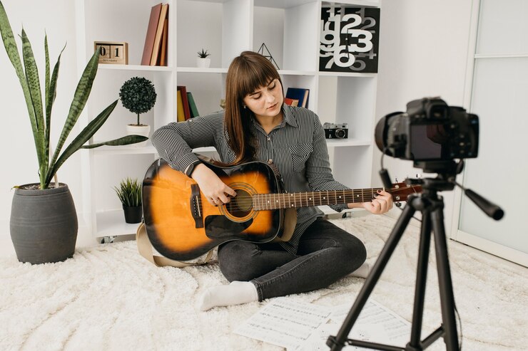 Foto gratuito blogger femenino streaming lecciones de guitarra con cámara