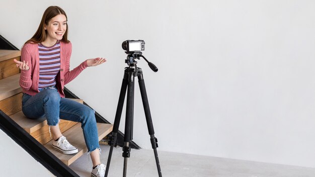 Blogger grabando con cámara y sentado en las escaleras