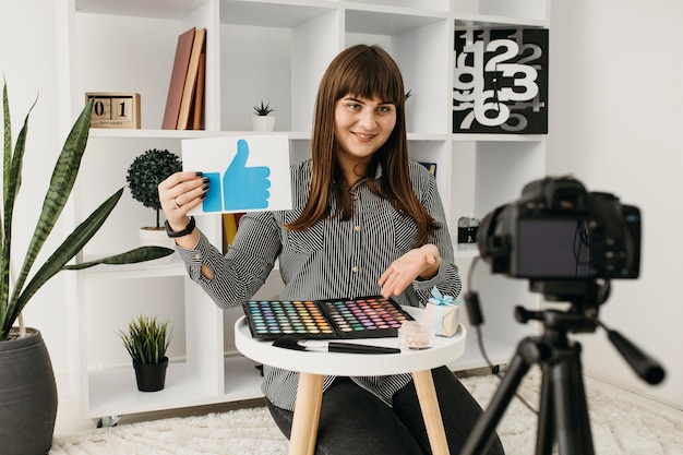 Blogger de maquillaje femenino sonriente con streaming en casa con cámara