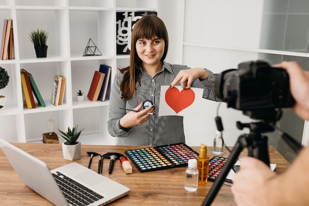 Blogger de maquillaje femenino con streaming con cámara y portátil en casa