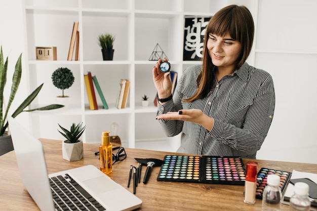 Blogger de maquillaje femenino con streaming con portátil en casa