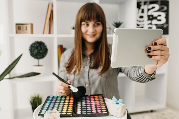 Blogger de maquillaje femenino con streaming con tableta en casa