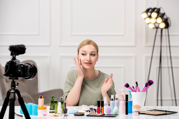 Blogger de maquillaje linda niña bonita grabando tutorial de maquillaje en cámara con crema en la cara