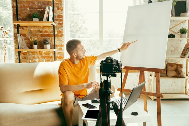 Blogger masculino caucásico con cámara de grabación de video revisión de gadgets en casa