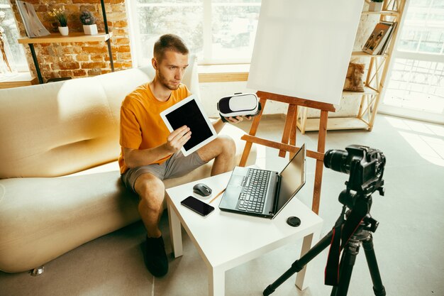 Blogger masculino caucásico con cámara de grabación de video revisión de gadgets en casa