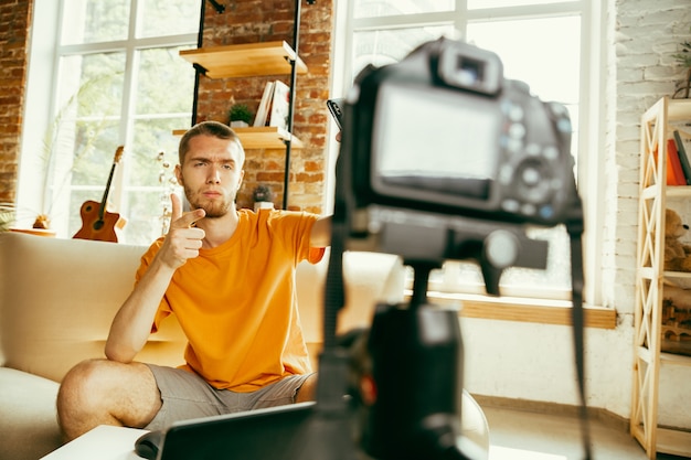 Blogger masculino caucásico joven con revisión de video de grabación de cámara profesional de gadgets en casa