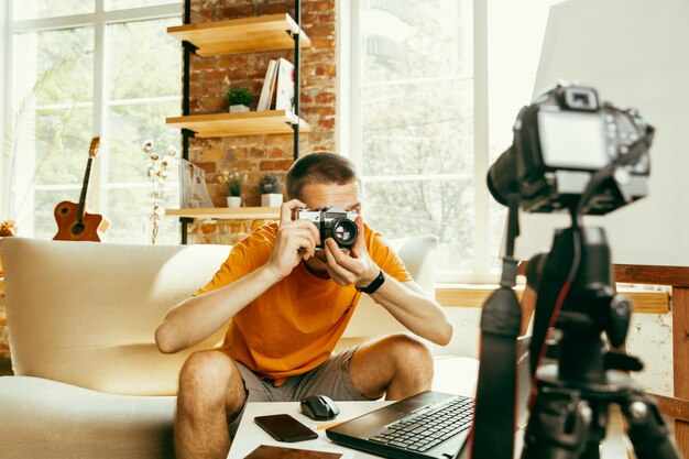 Blogger masculino caucásico joven con revisión de video de grabación de equipo profesional de cámara en casa