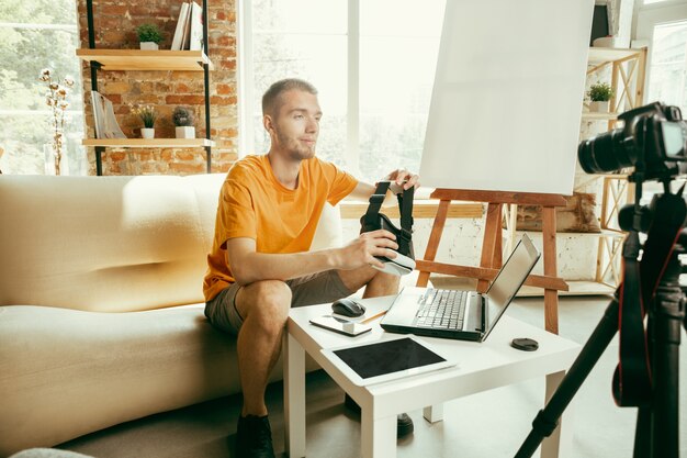 Blogger masculino caucásico joven con revisión de video de grabación de equipo profesional de gafas VR en casa.