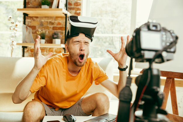 Blogger masculino caucásico joven con revisión de video de grabación de equipo profesional de gafas VR en casa.