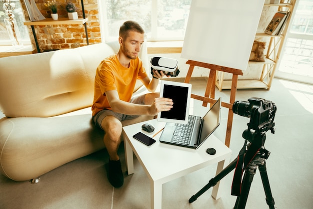 Blogger masculino caucásico joven con revisión de video de grabación de equipo profesional de gafas VR en casa