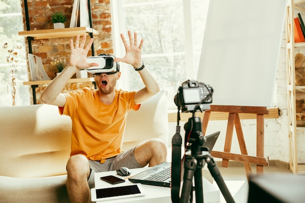 Blogger masculino caucásico joven con revisión de video de grabación de equipo profesional de gafas VR en casa