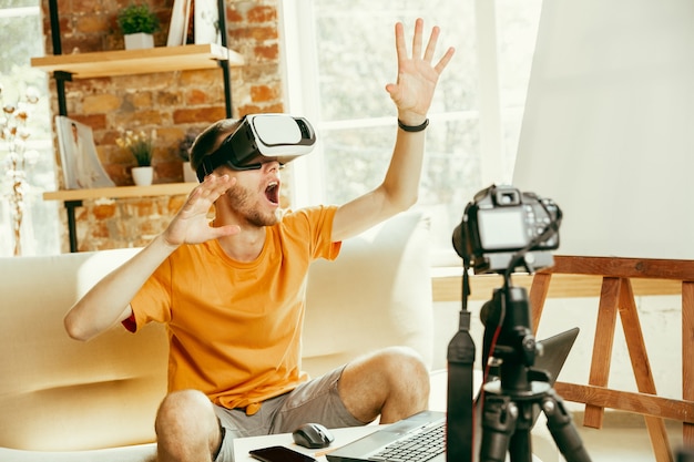 Blogger masculino caucásico joven con revisión de video de grabación de equipo profesional de gafas VR en casa.