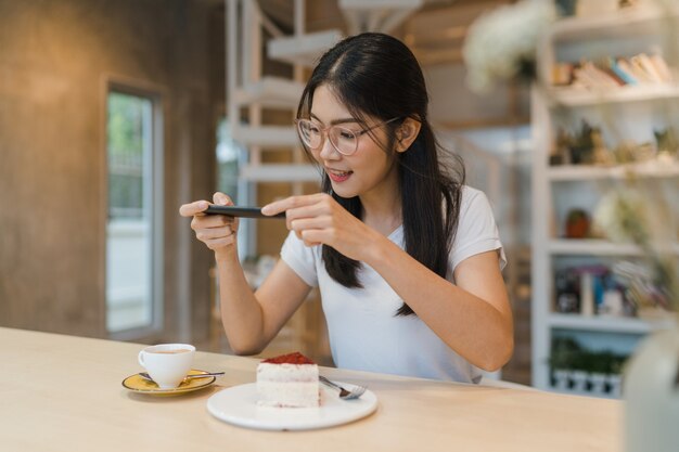 Blogger mujer asiática amigable influencer comer pastel en el café de la noche
