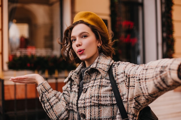 Blogger de mujer con estilo activo hace selfie en la pared del hermoso edificio