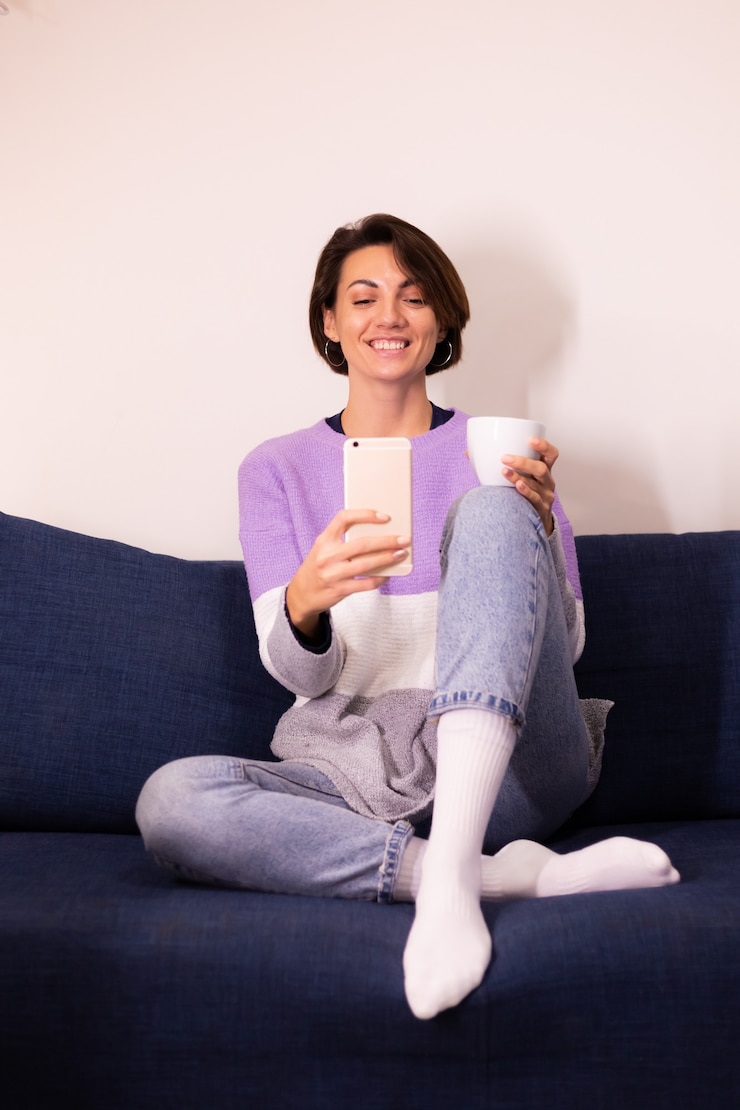 Foto gratuito blogger de mujer linda caucásica en casa en suéter de suéter púrpura cálido tomar selfie en espejo en el teléfono móvil