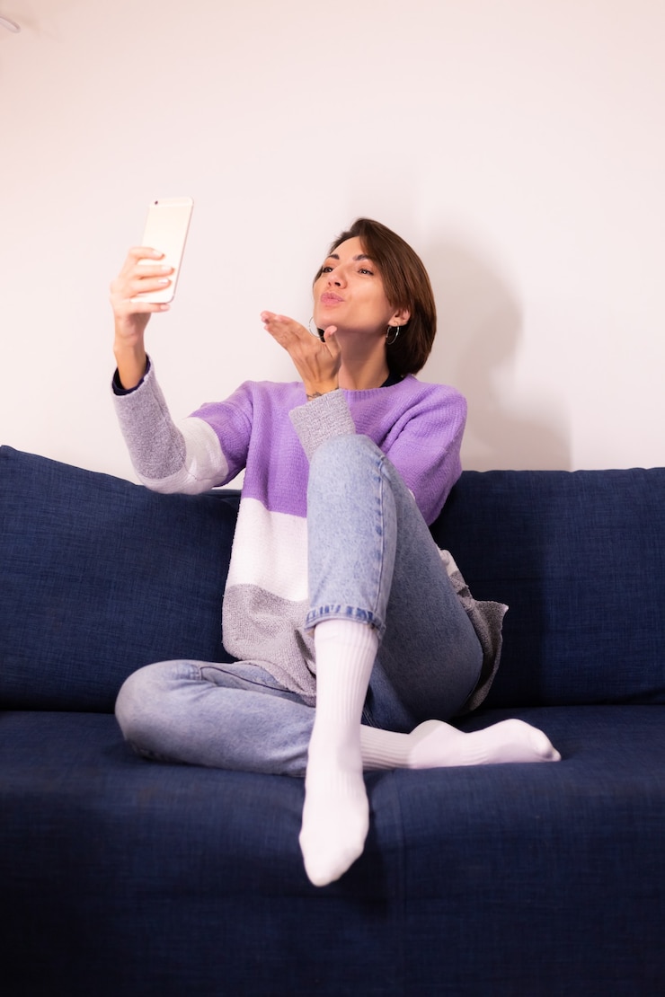 Foto gratuito blogger de mujer linda caucásica en casa en suéter de suéter púrpura cálido tomar selfie en espejo en el teléfono móvil