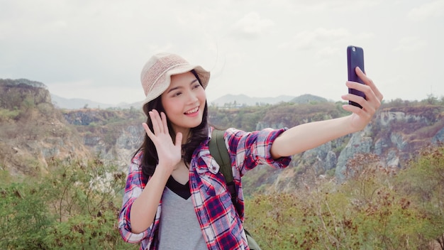 Blogger, mujer mochilera asiática, grabación de video vlog en la cima de la montaña, joven mujer feliz que usa el teléfono móvil para que el video vlog disfrute de las vacaciones en la aventura de senderismo.