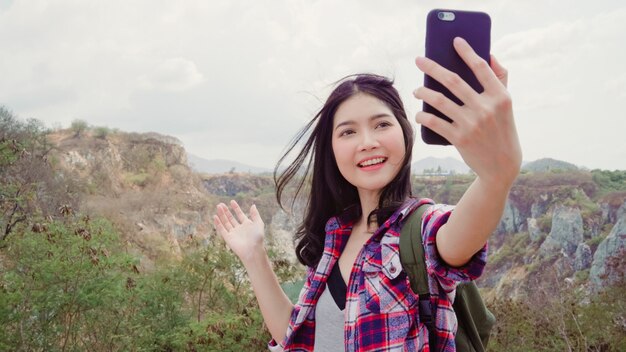 Blogger, mujer mochilera asiática, grabación de video vlog en la cima de la montaña, joven mujer feliz que usa el teléfono móvil para que el video vlog disfrute de las vacaciones en la aventura de senderismo.