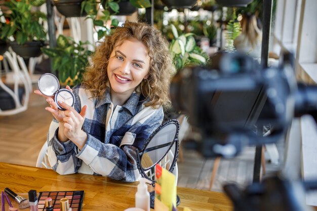 Blogger de mujer rubia está mostrando cómo maquillarse y usar cosméticos