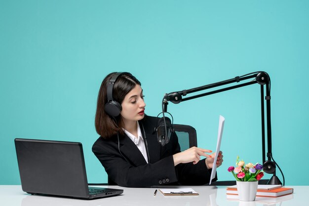 Blogger periodista encantadora joven en chaqueta negra grabando discurso en cámara leyendo notas