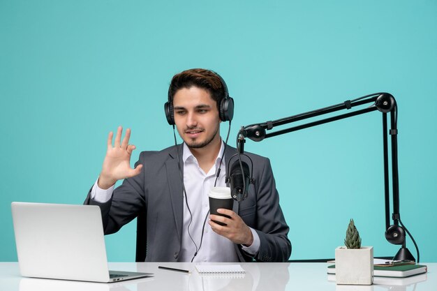 Blogger periodista joven lindo guapo en traje gris grabando video diciendo adiós