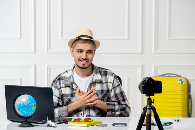 Blogger de viajes con sombrero de paja joven guapo grabando vlog de viaje en la cámara sosteniendo el cofre