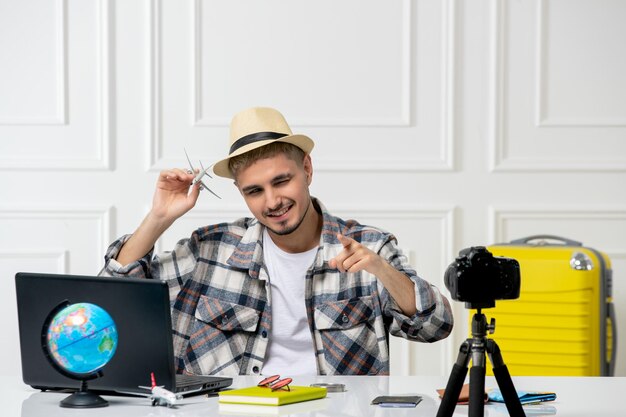 Blogger de viajes con sombrero de paja joven guapo grabando vlog de viaje en cámara volando al extranjero