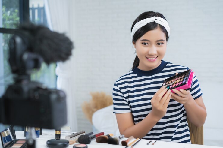 Foto gratuito la bloguera de belleza presenta cosméticos de belleza mientras se sienta frente a la cámara para grabar video
