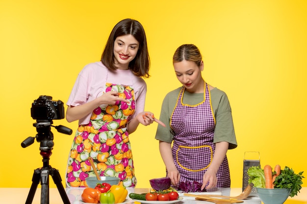 Bloguera de comida linda cocinera fitness grabando video para redes sociales con un colega cortando verduras