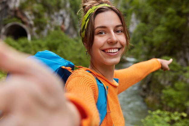 Bloguera positiva graba videos en línea mientras explora la naturaleza y señala la distancia