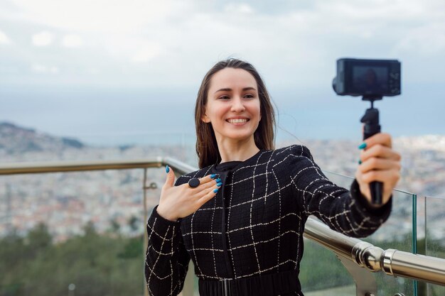 La bloguera sonriente se está tomando una selfie mostrando su anillo a la cámara contra el fondo de la vista de la ciudadxDxA