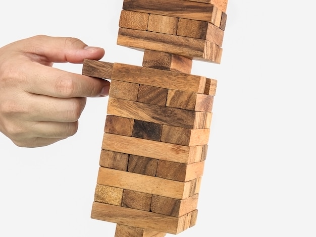 Bloque de madera inclinado juego de jenga torre con mano, concepto de riesgo