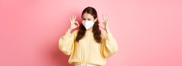 Foto gratuita bloqueo de covid y concepto de pandemia joven sonriente te asegura guiñando un ojo y mostrando el signo de estar bien alri