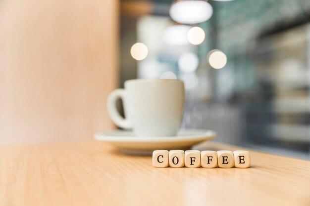 Bloques cúbicos de café con taza de café en la mesa de madera