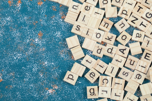 Foto gratuita bloques de letras hechos de madera y aislados en la superficie del patrón azul