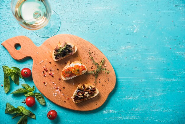 Bocadillos de tostadas con tomillo; Albahaca y tomates y vino sobre fondo pintado.