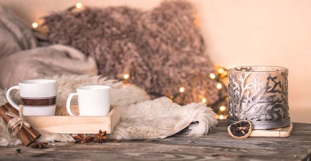 Bodegón ambiente hogareño en el interior con tazas y velas en la mesa de colchas acogedoras