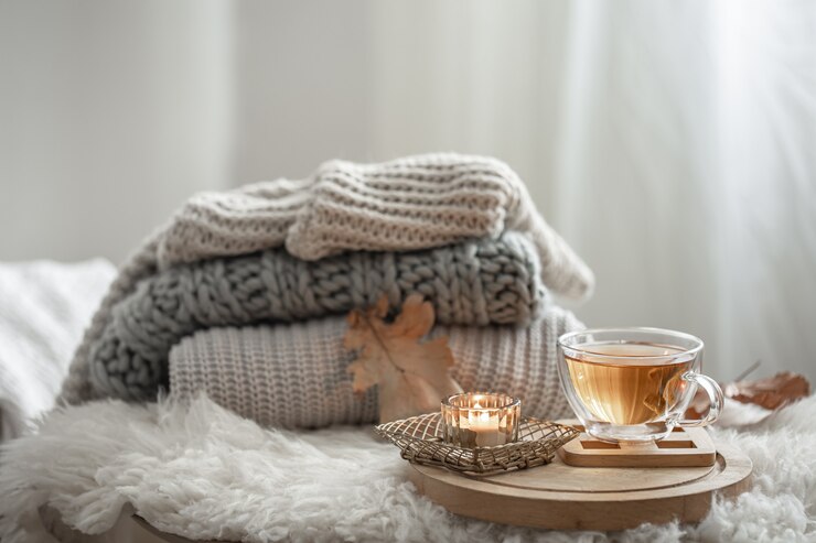 Foto gratuito bodegón casero con suéteres de punto y una taza de té sobre un fondo borroso.