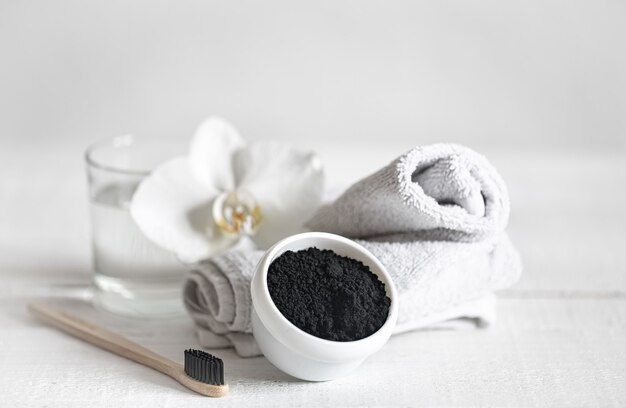 Bodegón con un cepillo de dientes de madera orgánica con un vaso de agua y polvo blanqueador de dientes natural. Higiene bucal y cuidado dental.