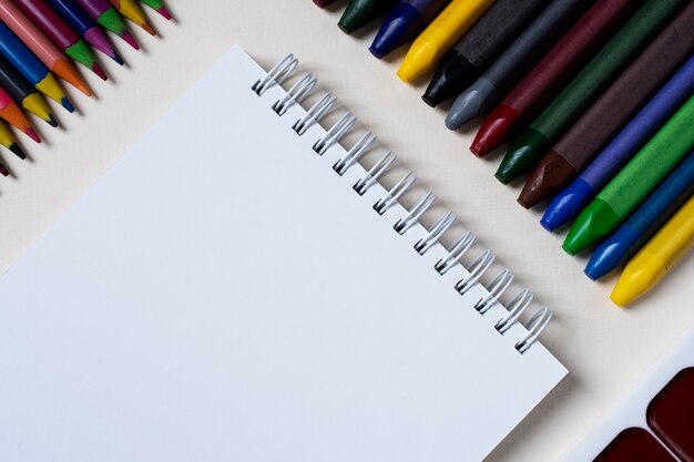 Bodegón de cuaderno, lápices y crayones.