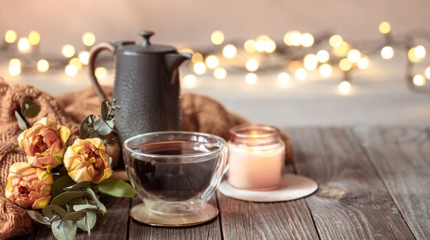 Bodegón festivo con una taza de bebida, flores y detalles de decoración sobre un fondo borroso con bokeh.