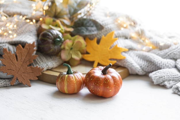 Bodegón otoñal con hojas de calabaza y elemento tejido