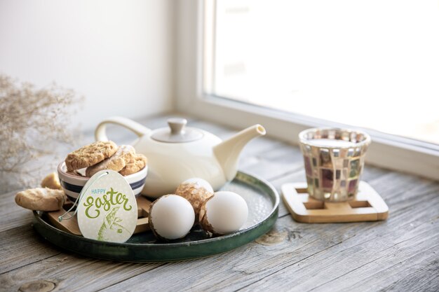 Bodegón de Pascua casera con té y galletas en el alféizar de la ventana por la mañana