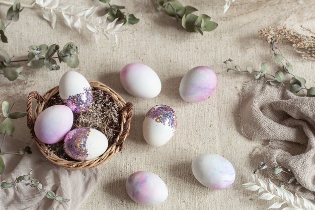 Bodegón de Pascua con huevos decorados con lentejuelas en una canasta de mimbre. Concepto de pascua feliz